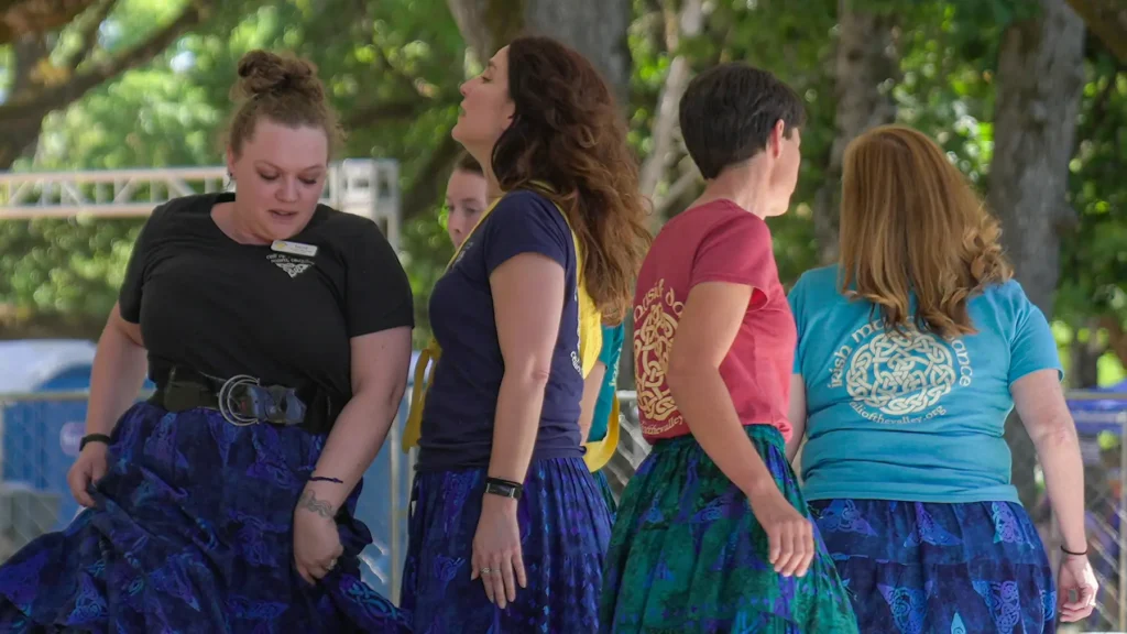 Women from Ceili of the Valley dance in a circle on the cultural demo stage