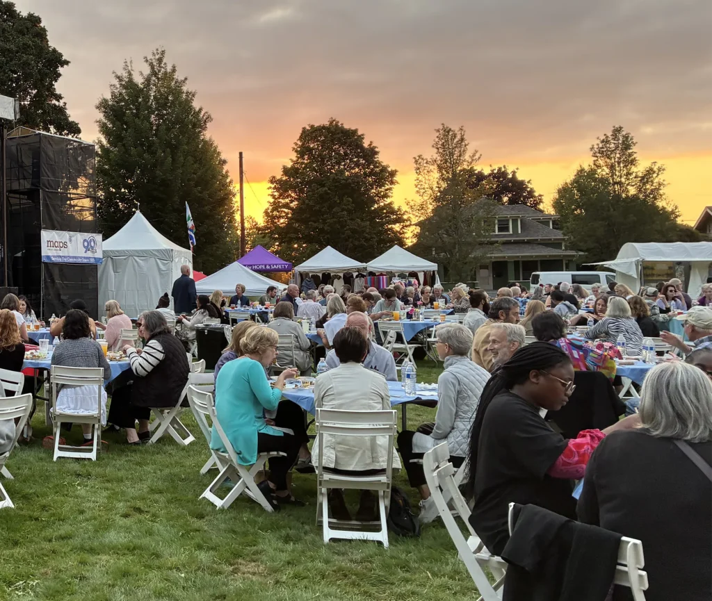 Several tables of patrons dining outdoors in a grassy area